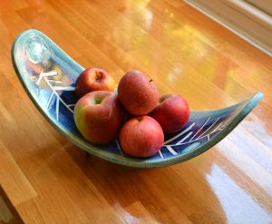a three legged ceramic fruit bowl with apples